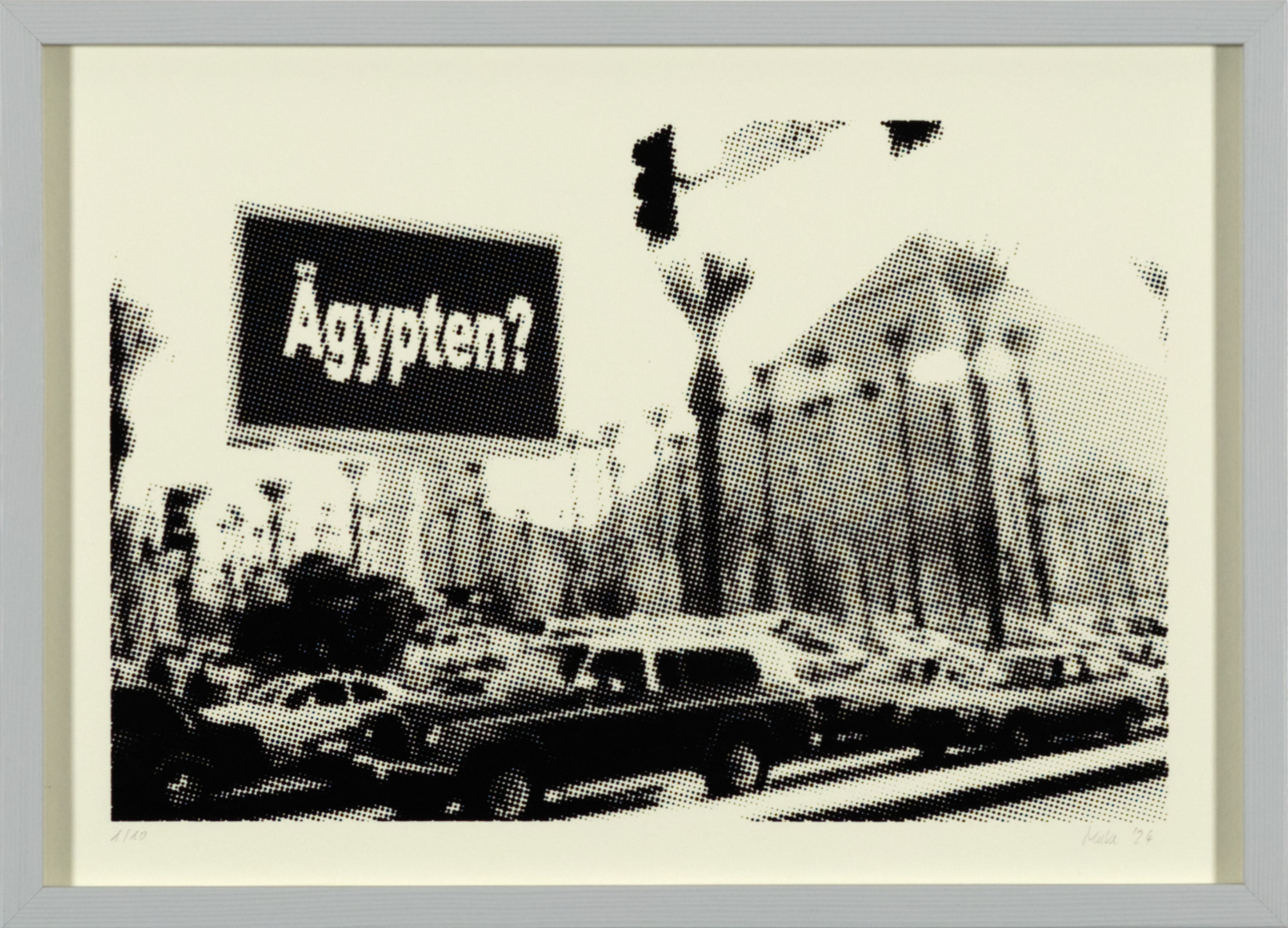 Bild im Querformat. Auf gebrochen weißem Papier ist ein gerastertes schwarzweißes Bild zu sehen. Im Vordergrund sieht man viele Autos im Stau, wahrscheinlich an einer Ampel, da von oben eine Ampel ins Bild ragt. Im Mittelgrund links steht ein großes Schild mit der Aufschrift: "Ägypten?" und ein Wald aus einheitlich zurecht gestutzten Palmen. Recht im Hintergrund kann man im Dunst eine große Pyramide erkennen.
Das Bild hat einen grauen Rahmen.